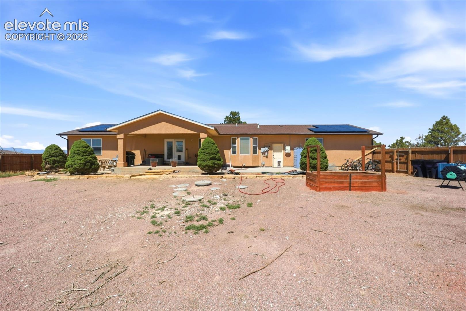South-facing stucco exterior with a covered patio and multiple solar panels