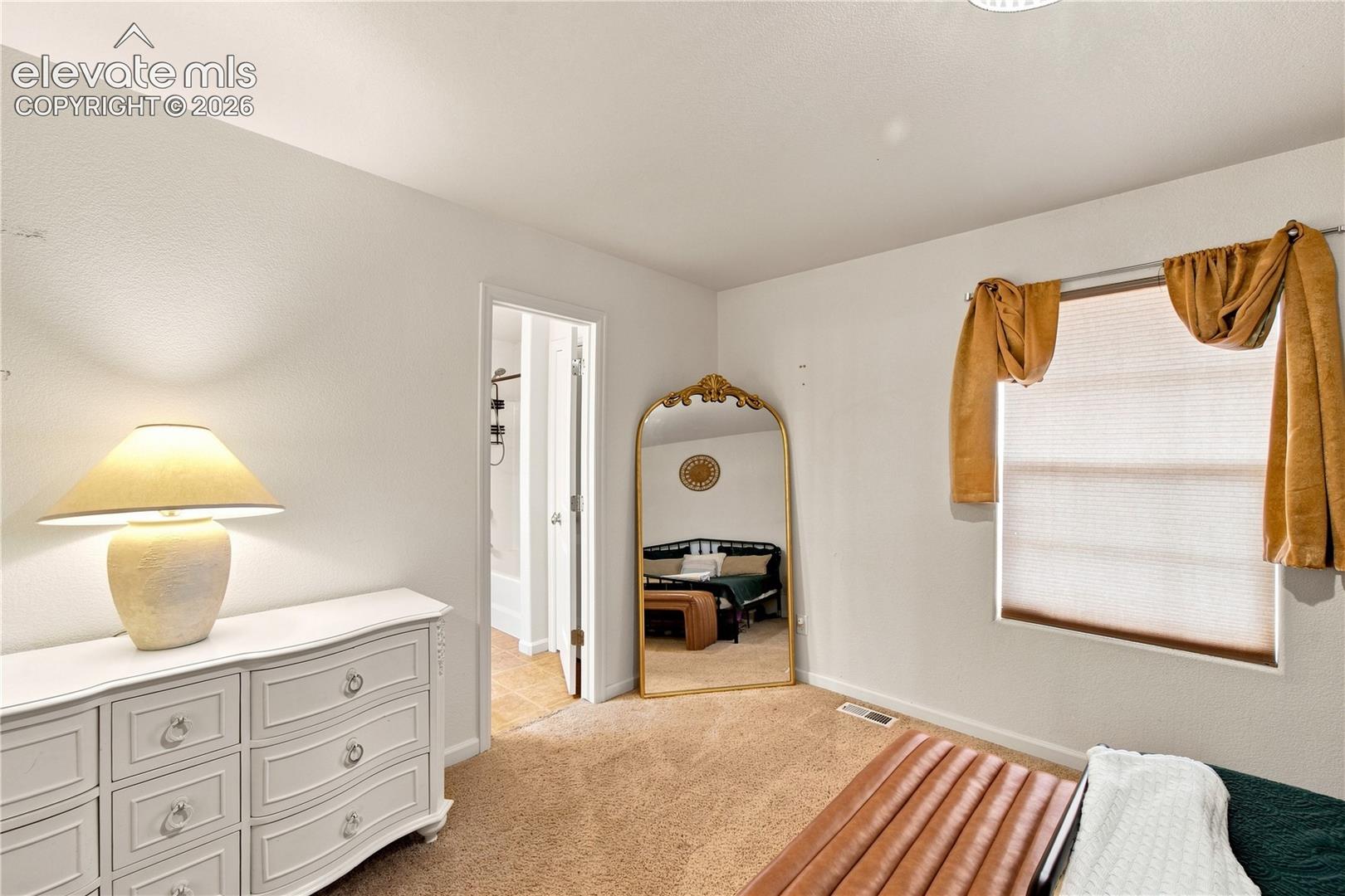 Carpeted flooring, white walls, and a window with blinds