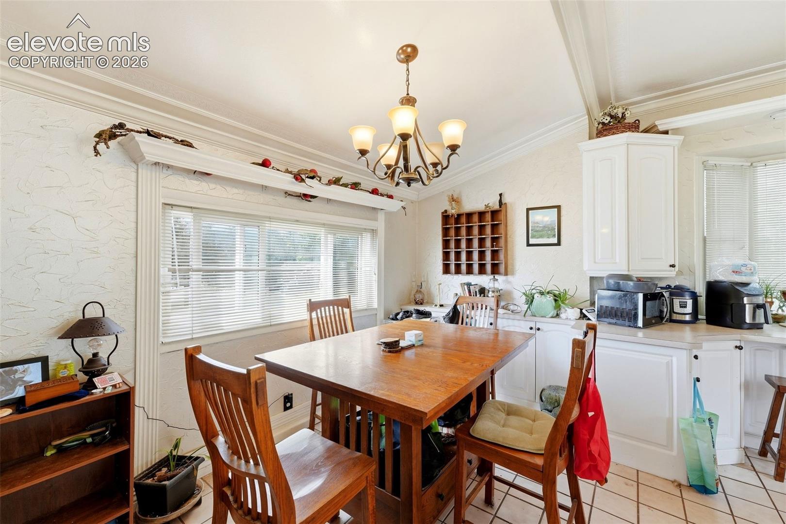 Kitchen area with white cabinetry, light-toned countertops, and a bay window