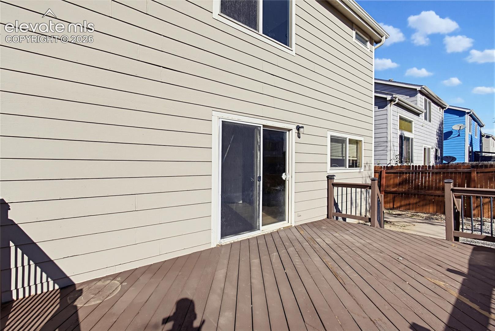 Exterior rear elevation featuring horizontal lap siding, a sliding glass door, and an elevated wood deck with perimeter railing