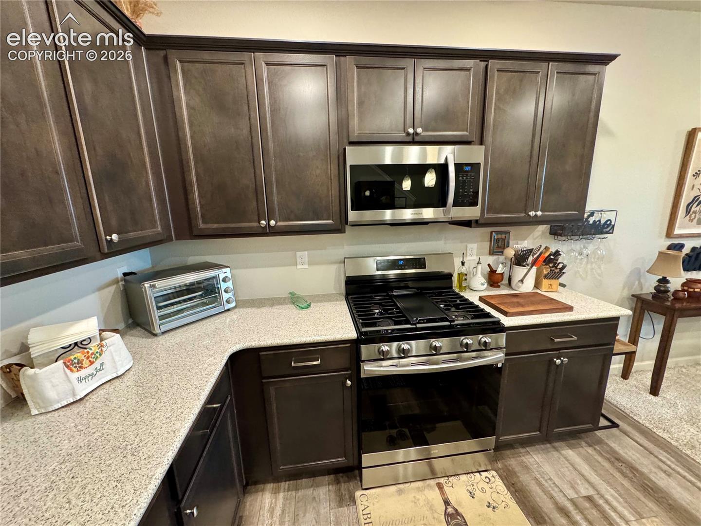 Kitchen featuring dark-toned cabinetry, light-colored countertops, stainless steel gas range, and a mounted stainless steel microwave