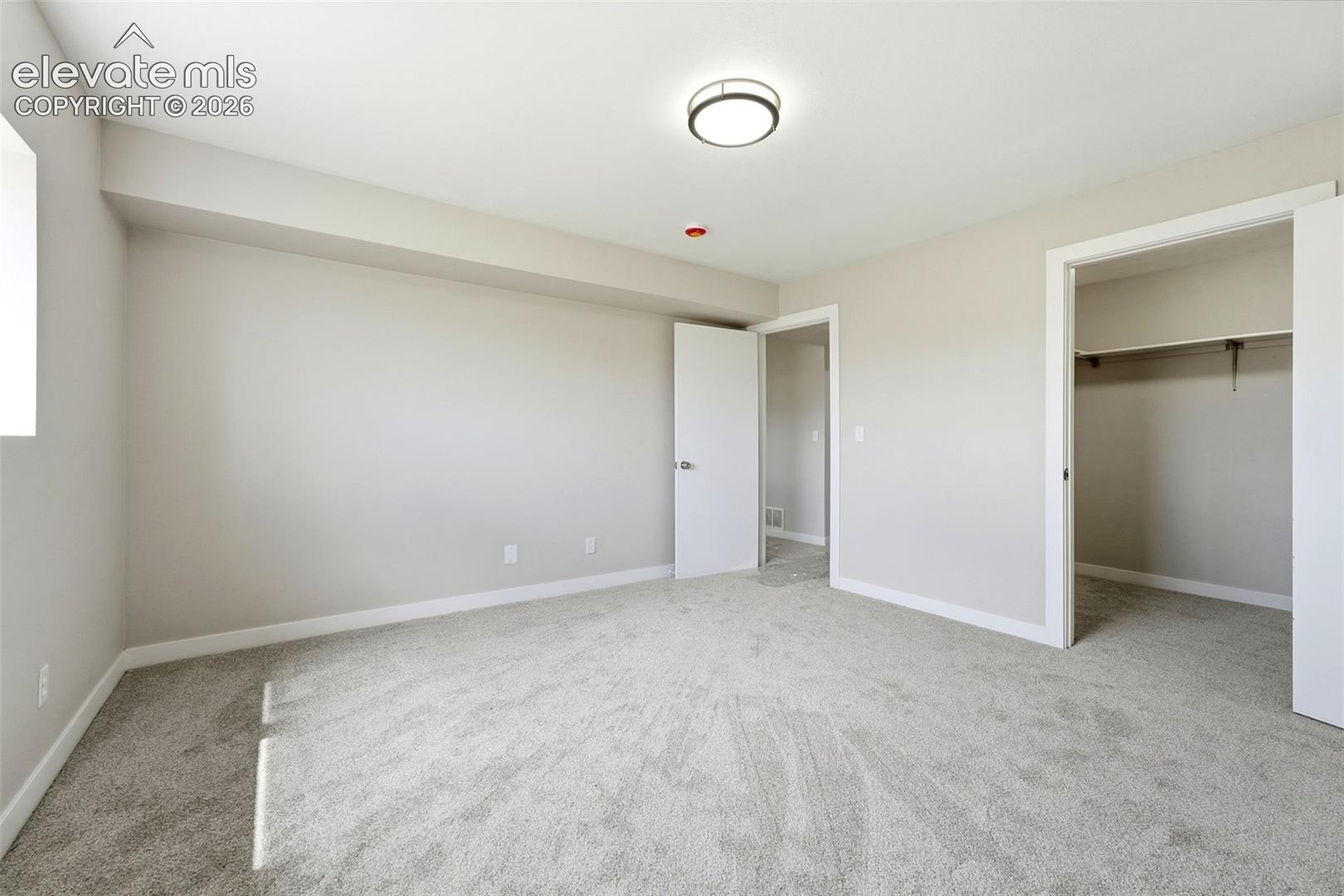 Neutral-toned walls with light gray carpeting, featuring a modern flush-mount ceiling light
