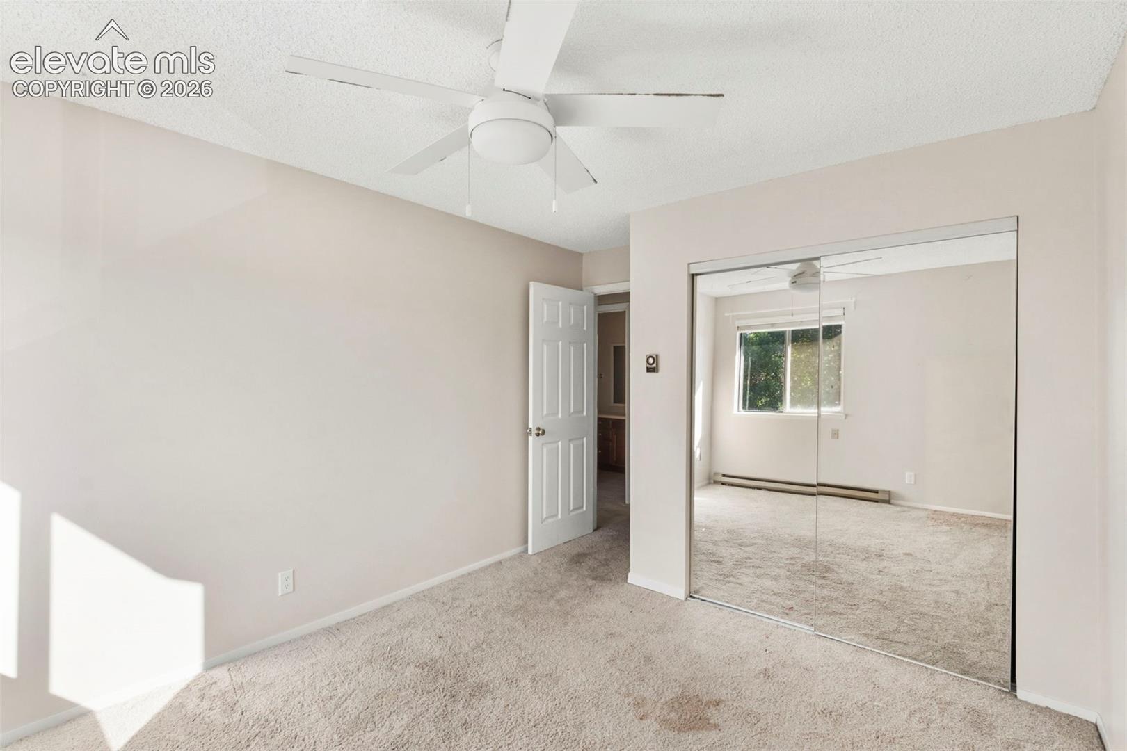 Room featuring a ceiling fan, neutral wall paint, and mirrored closet doors