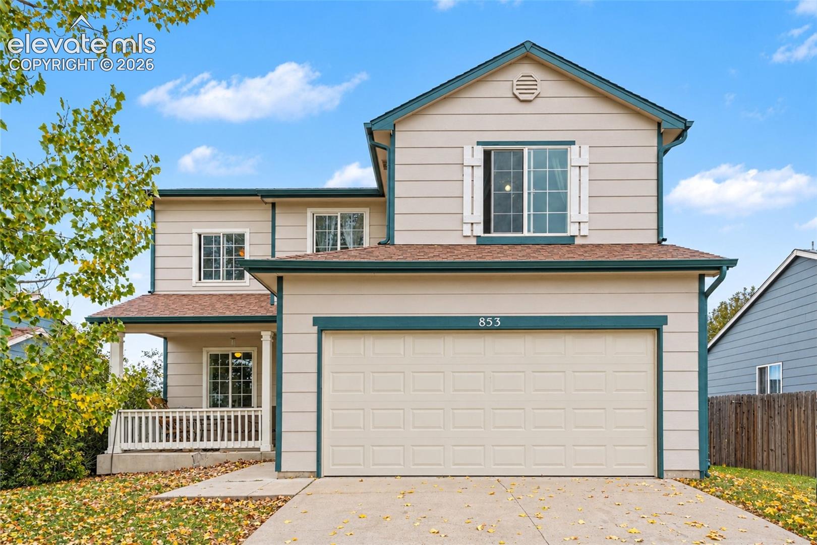Two-story residence featuring horizontal lap siding, a front porch with decorative railing, an attached two-car garage, and shutter-framed windows