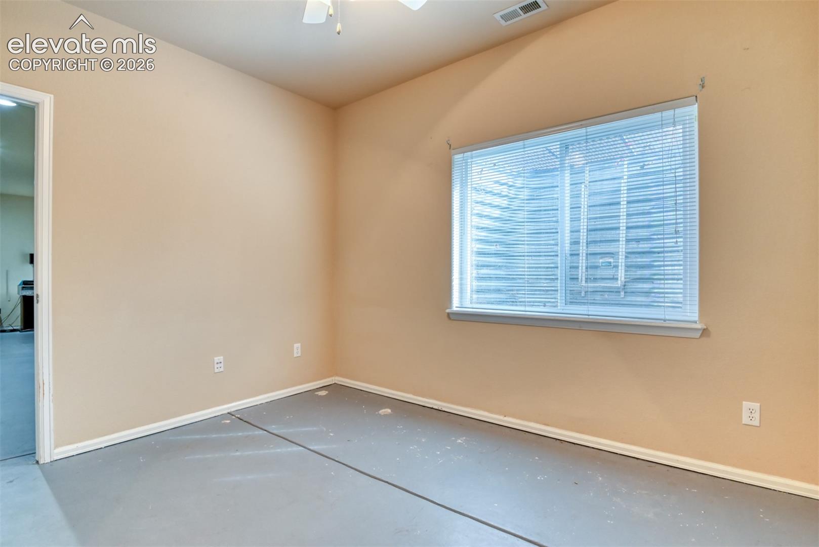 Room featuring neutral-toned walls, high ceilings, large window with horizontal blinds, ceiling fan, and concrete flooring