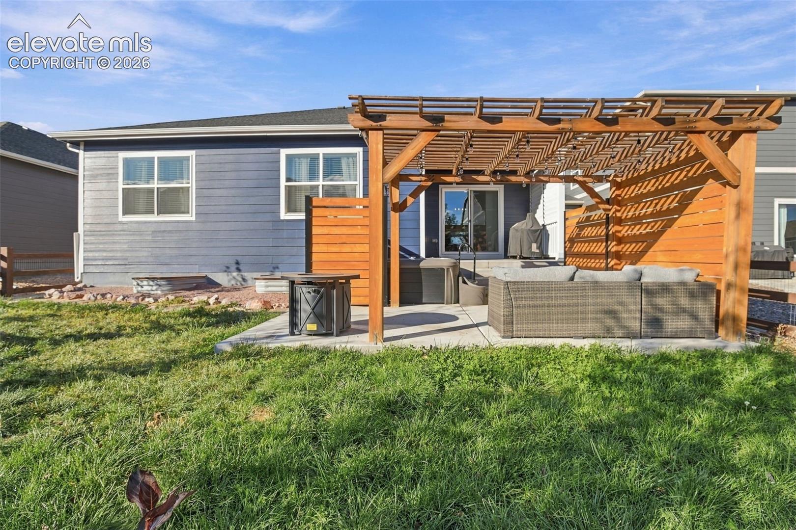 Rear exterior featuring horizontal lap siding, a wood-frame pergola, a concrete patio, and a wood privacy screen