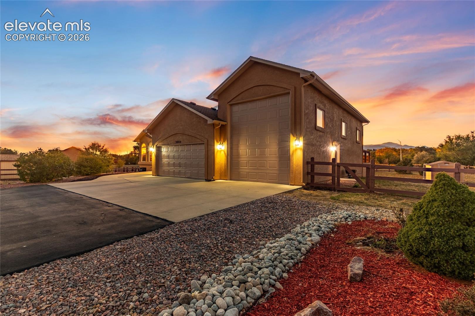 Stucco exterior featuring a double garage and RV garage, concrete pad and pavement driveway, xeriscape landscaping, Pikes Peak in the backgrounc 