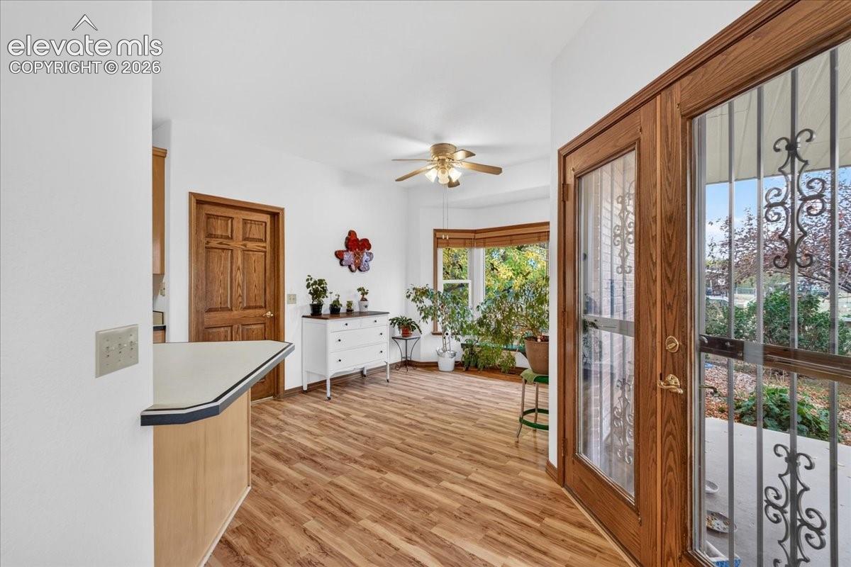 Wood-finish flooring, bay window, ceiling fan, and wooden entry door with decorative security screen