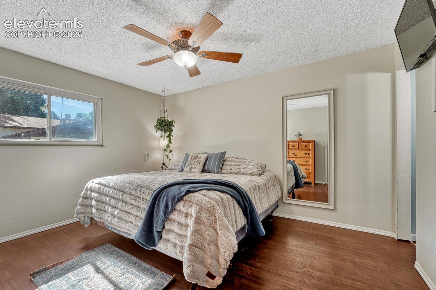 The private Primary Suite features dual closets, a ceiling fan, & an adjoining bath with a tiled shower. 