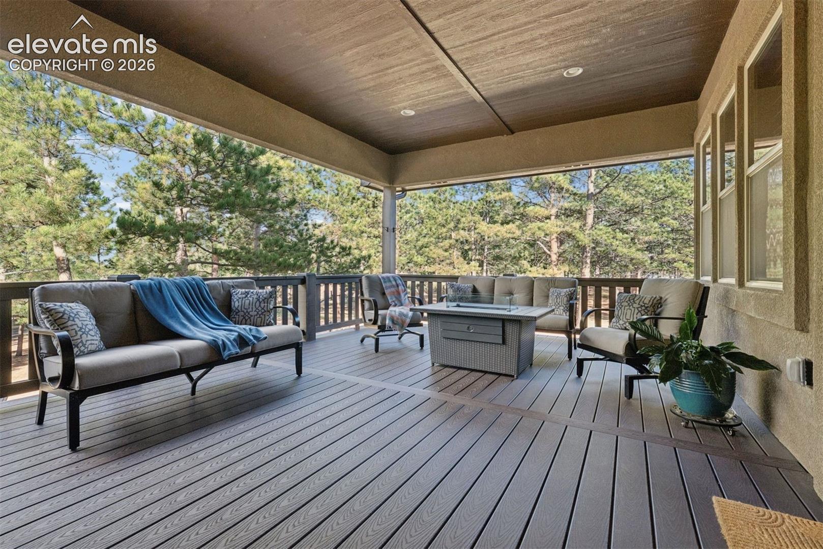 Covered outdoor deck featuring composite decking, a wood-paneled ceiling with recessed lighting, and a protective railing