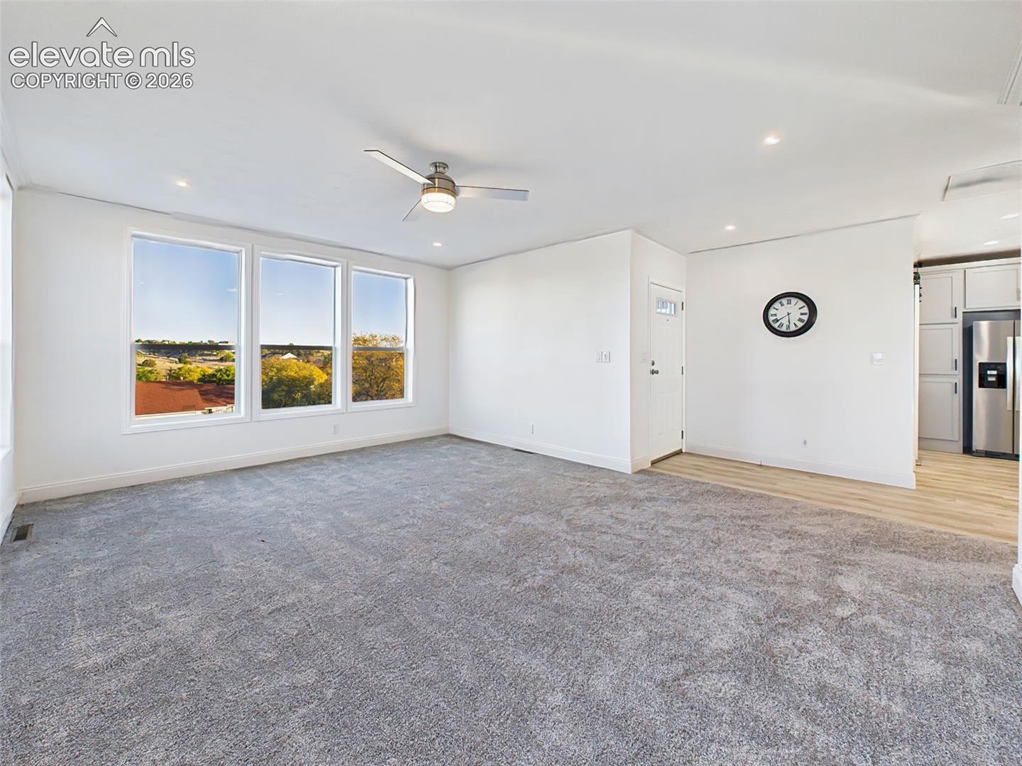 Unstaged version of the main living area, highlighting the fresh paint, new carpet, and seamless flow into the kitchen.
