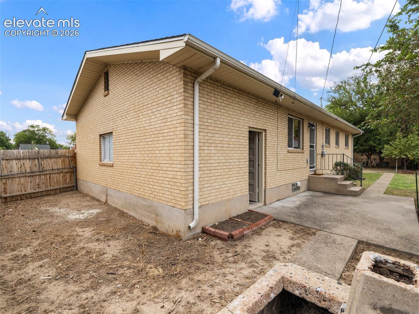 Brick exterior with multiple windows and a concrete patio