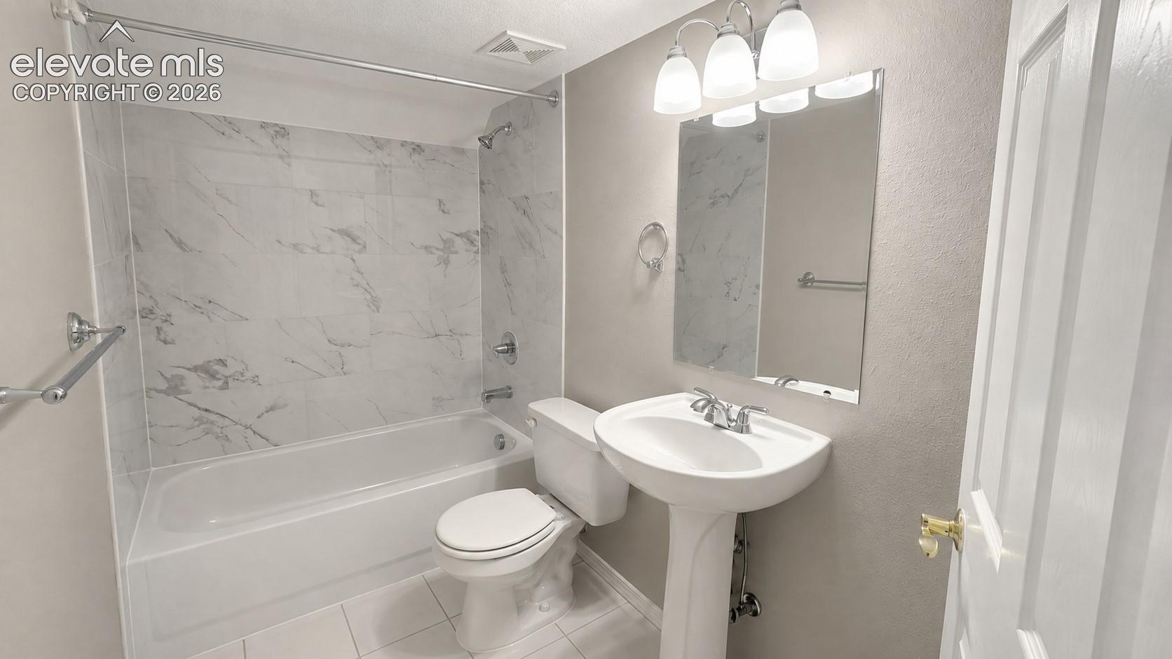 Pedestal sink with chrome faucet, wall-mounted mirror, three-light vanity fixture, bathtub with tile surround, and white toilet