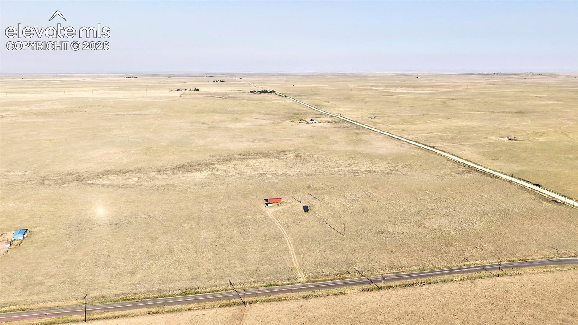 Expansive rural land featuring a paved road and clear skies