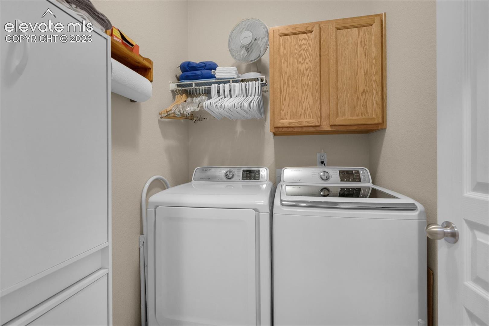 Dedicated laundry area featuring light-toned walls, built-in wooden cabinetry, and overhead wire shelving