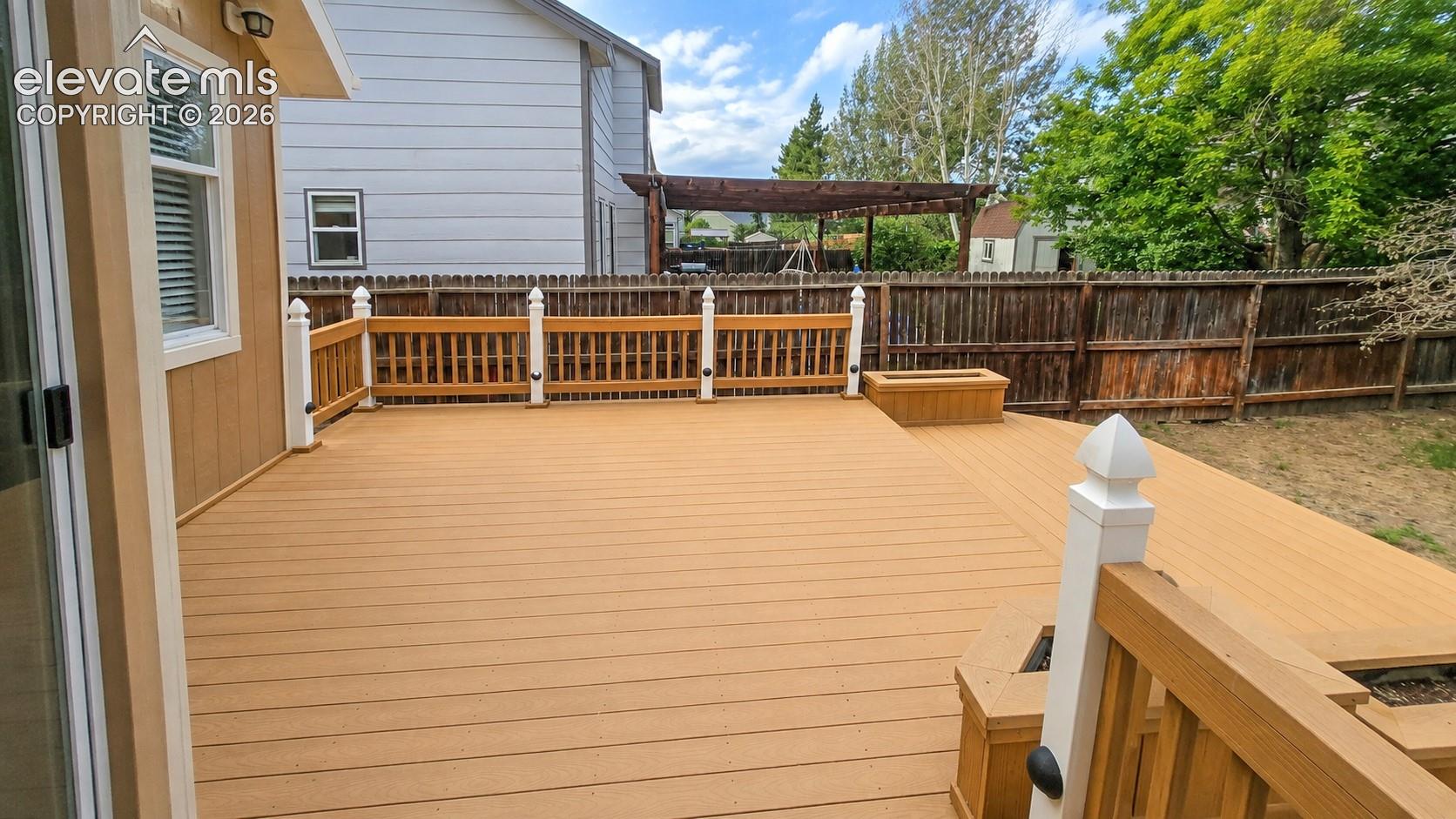 Expansive multi-level composite deck with white balusters and wood-finish railings, featuring a built-in planter box