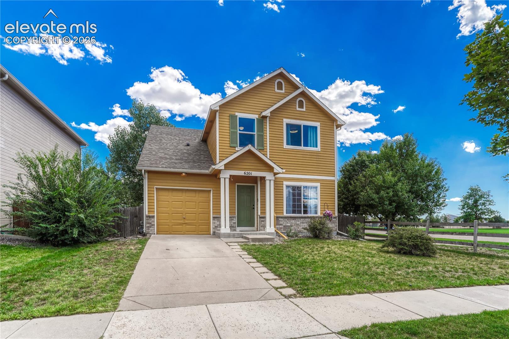 Two-story residence featuring lap siding, stone veneer accents, a covered front porch with decorative columns, and an attached single-car garage