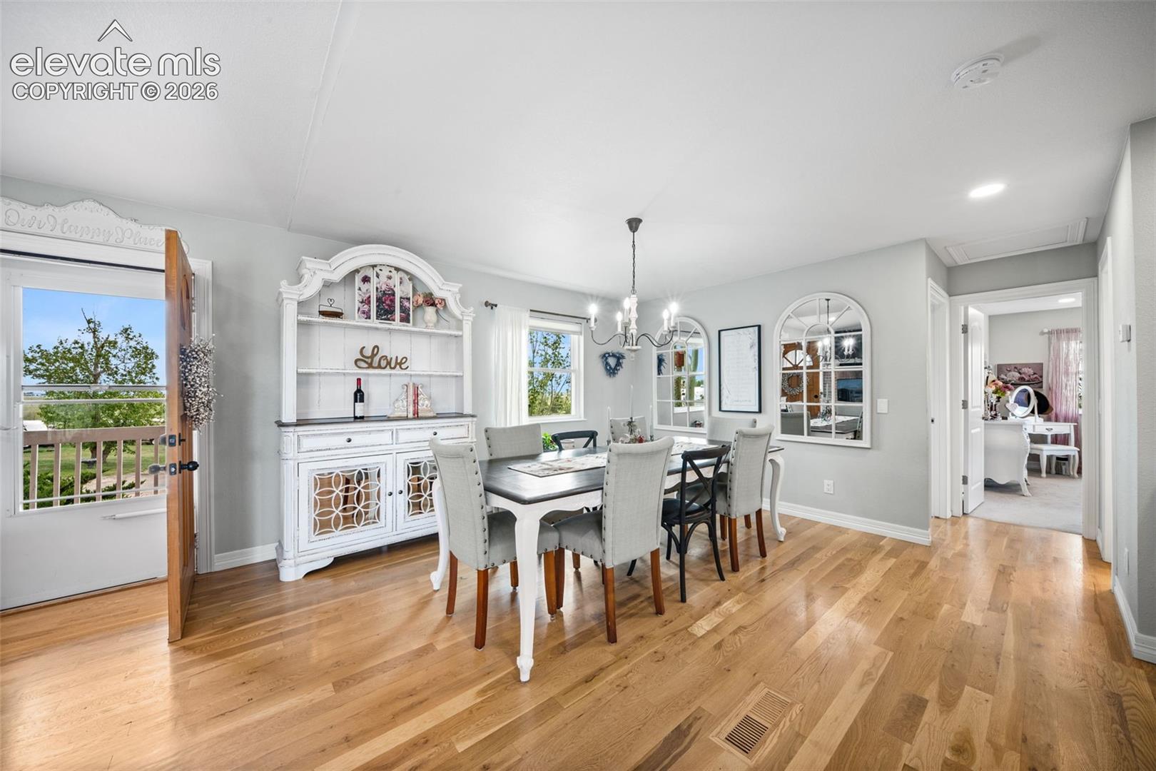 Dining area featuring wood-finish flooring, a contemporary chandelier, light gray wall paint, and natural light from multiple windows