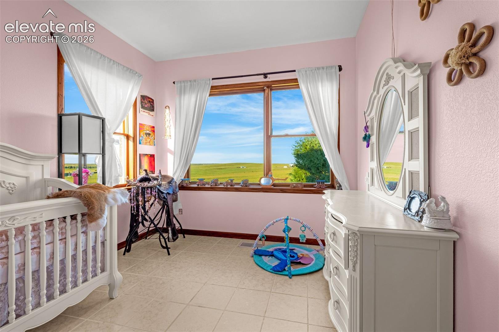 Tile flooring, multiple windows with wood trim, and a high ceiling