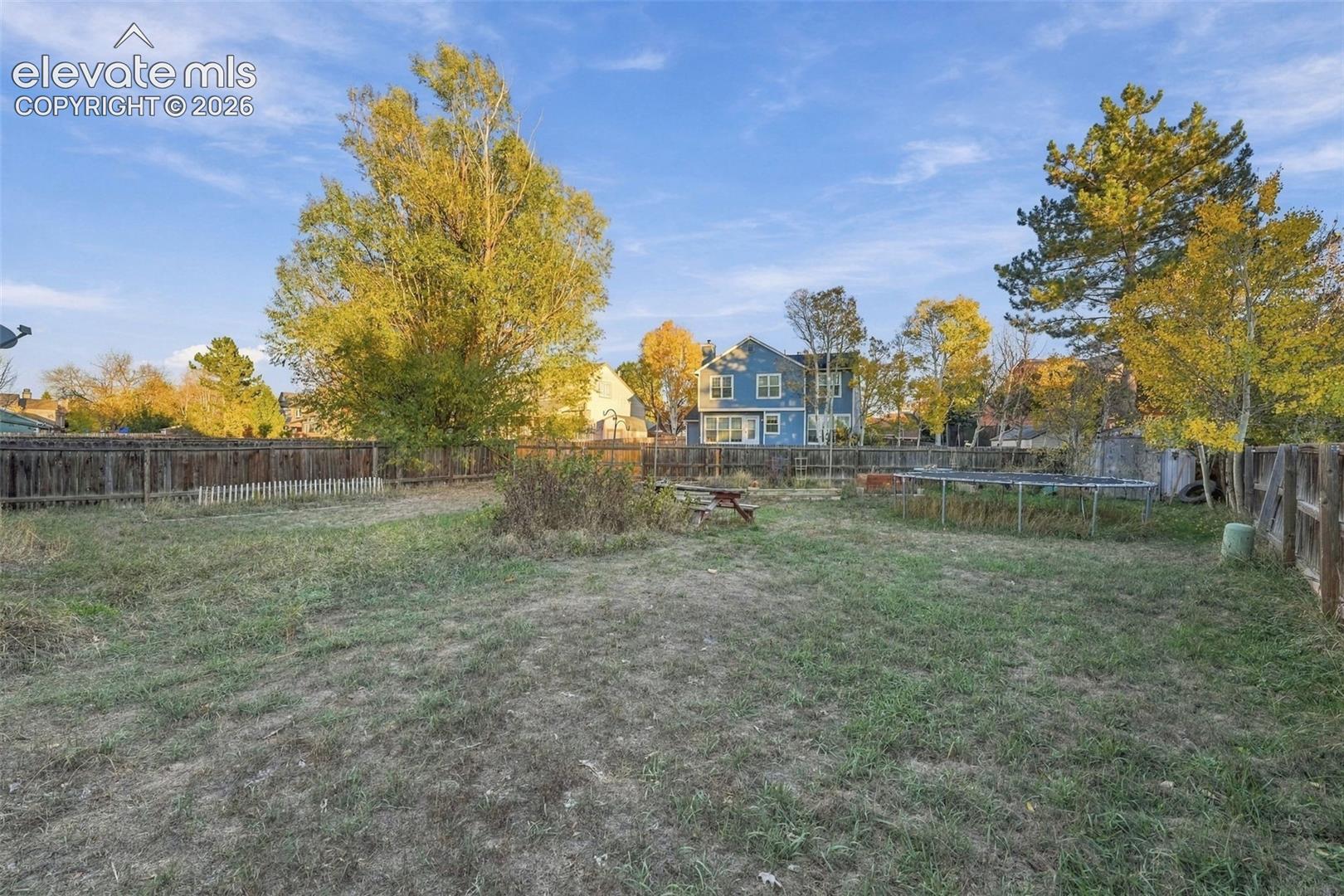 Expansive backyard featuring a wood fence perimeter and mature trees