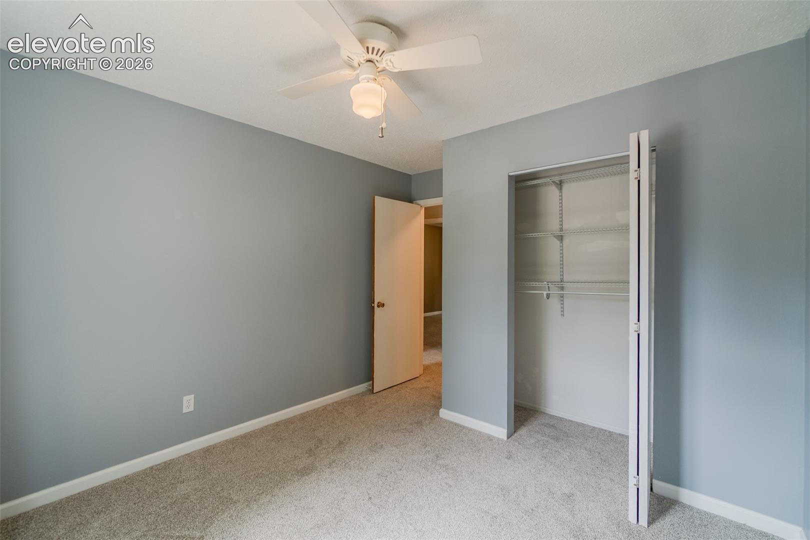 Carpeted flooring, ceiling fan, bi-fold closet, and neutral wall color