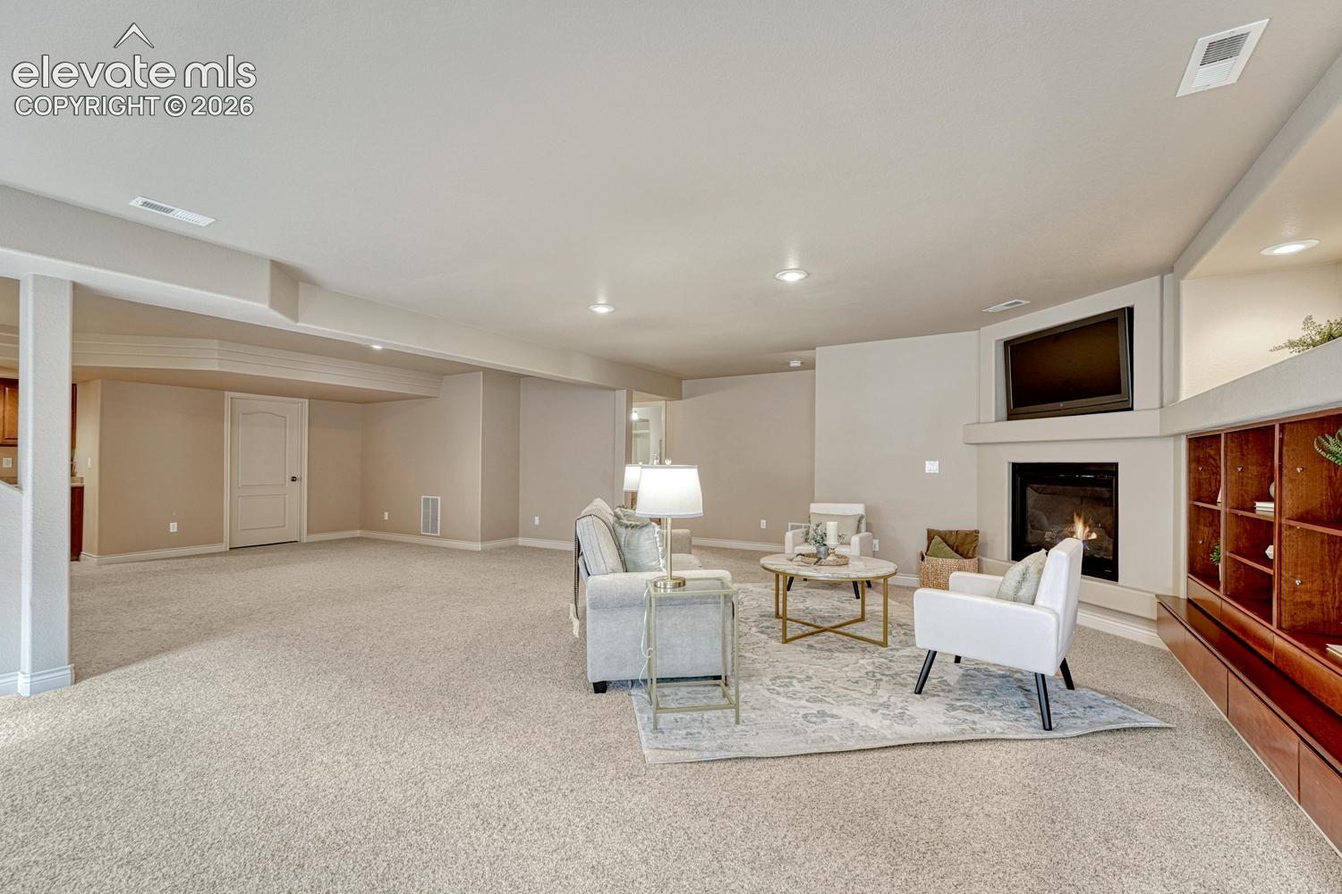 Large Basement Family Room with neutral carpet, gas fireplace, TV niche, and built-ins.