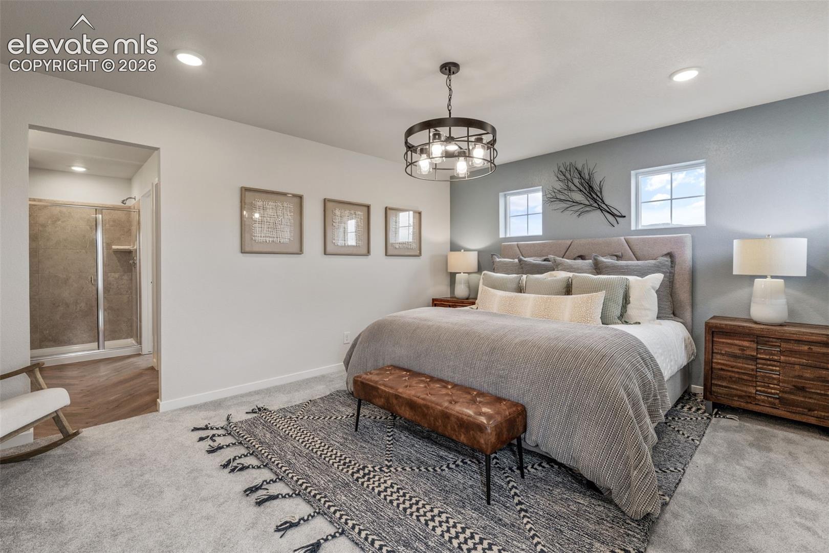 bedroom with upholstered bed, two small high windows and gray accent wall, visible doorway to tiled shower