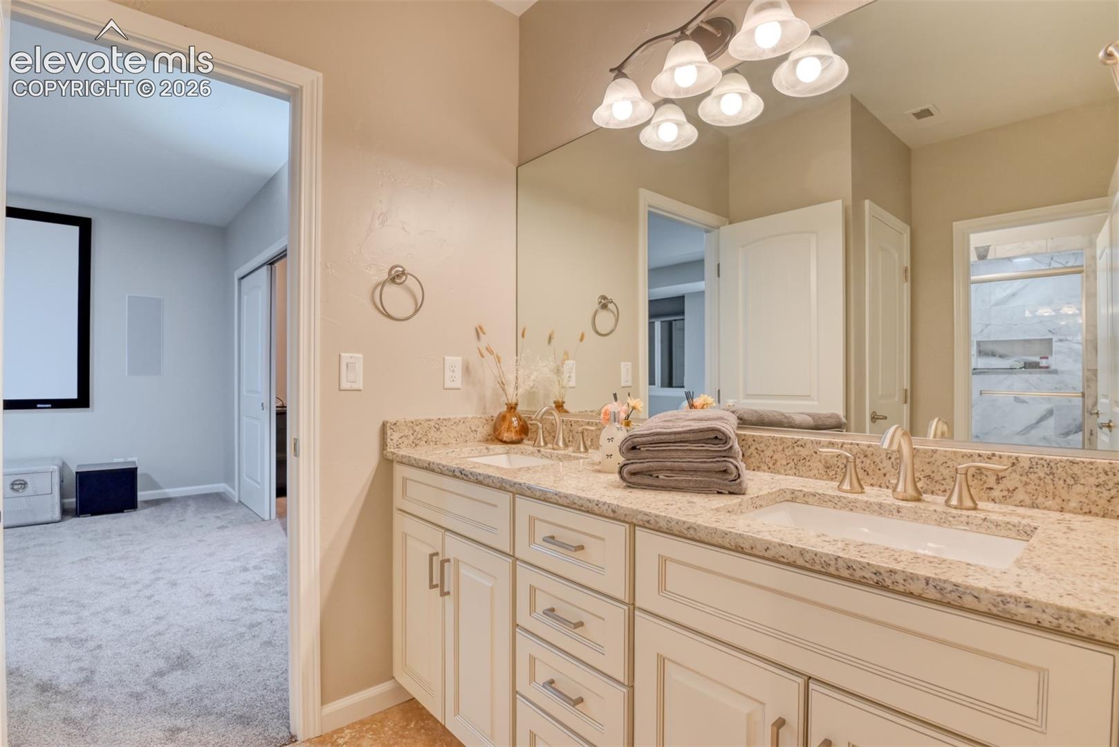 Dual vanity with integrated sinks, light-toned countertop, and white cabinetry with brushed nickel hardware.