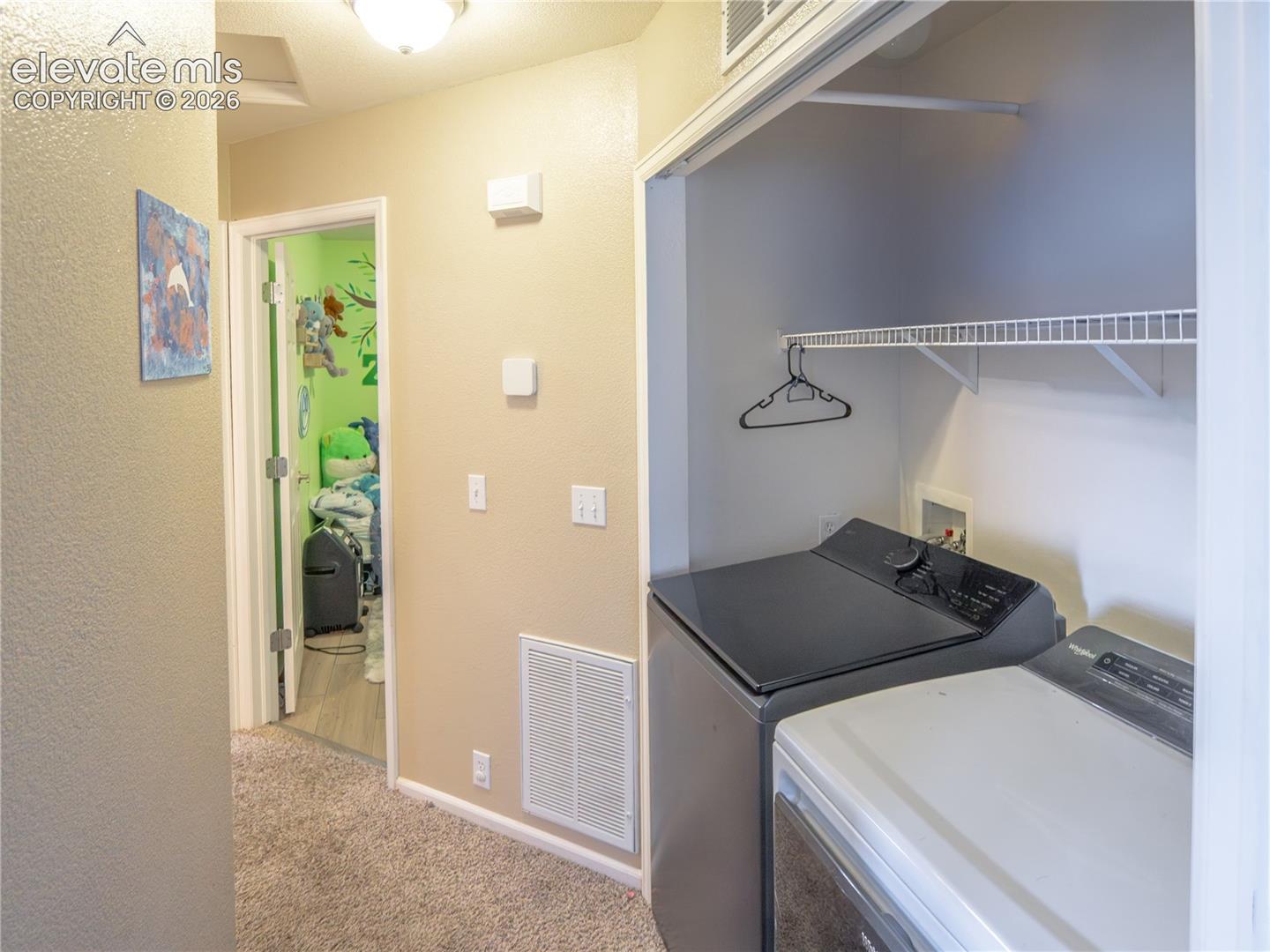 Dedicated laundry closet featuring a wire shelf and clothing rod, positioned off a carpeted hallway