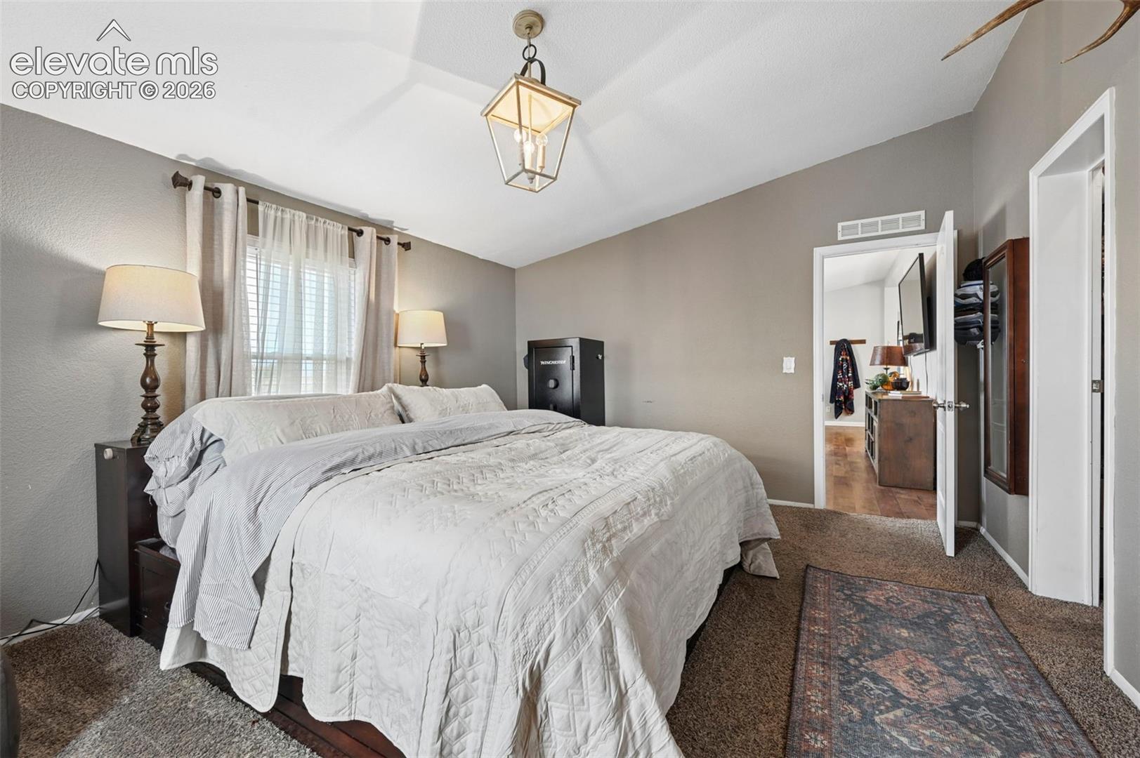 Vaulted ceiling, four-light pendant fixture with a brass finish, neutral wall color, and wall-to-wall carpeting