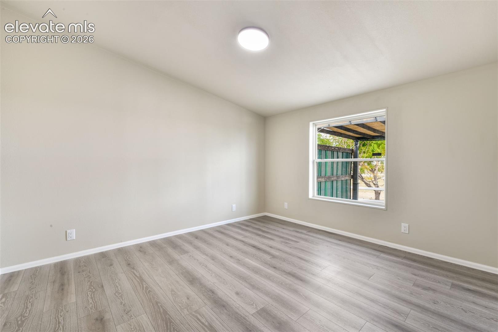 Light gray wood-finish flooring, neutral wall paint, and a white-framed window