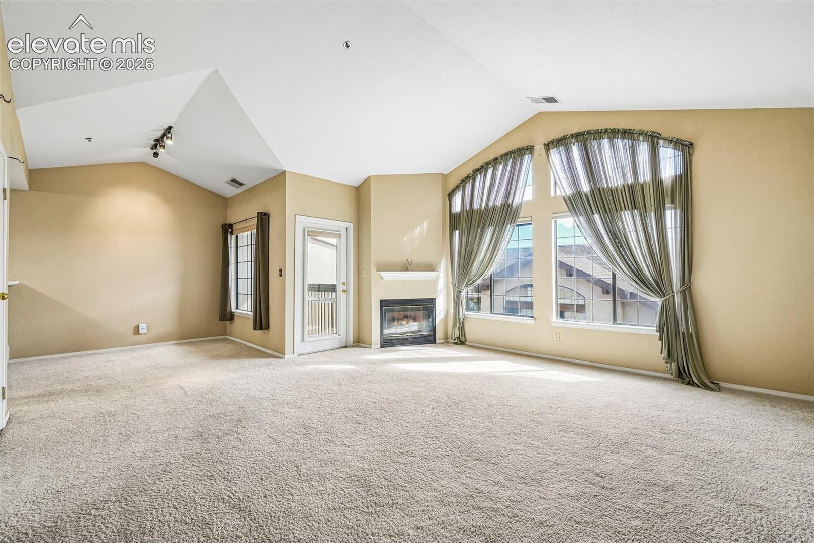 Living room with vaulted ceilings, a gas fireplace, a walk out and large windows brining in tons of natural light