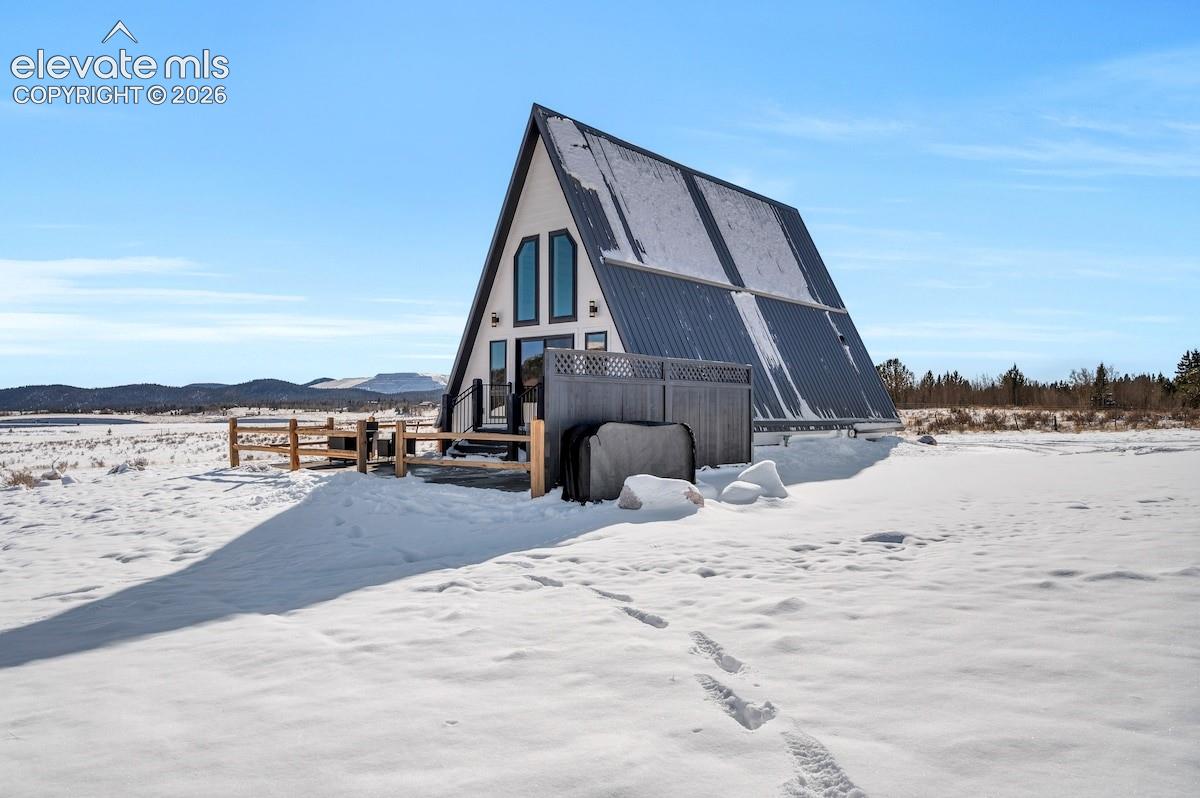 A-frame architectural exterior featuring a metal roof, tiered windows, and an enclosed deck area with wood-style perimeter fencing