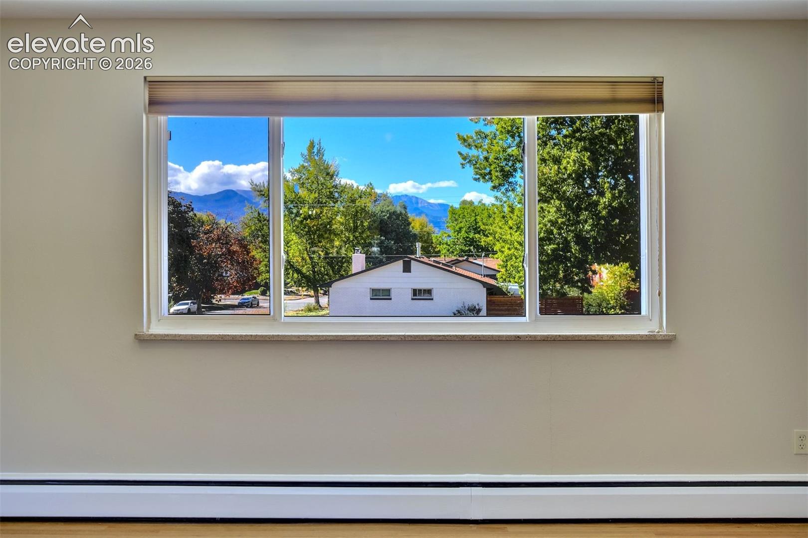 Large picture window with a stone-finish sill, showcasing a mountain backdrop and mature trees
