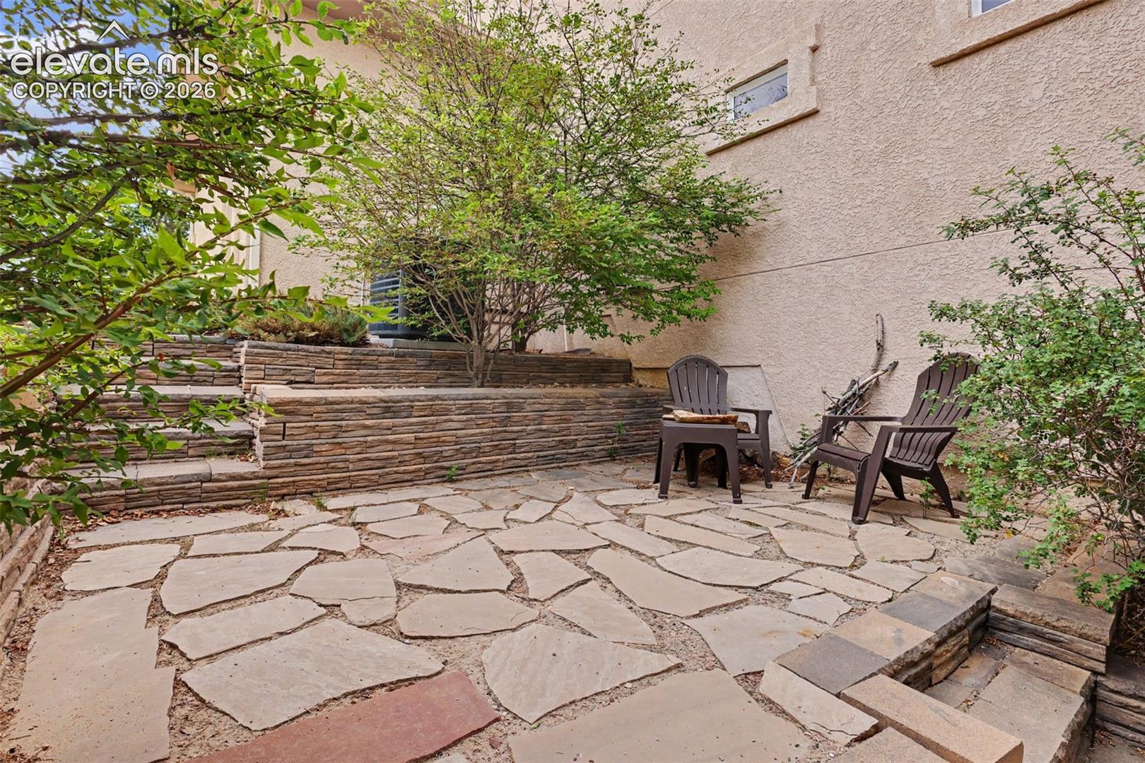 Expansive flagstone patio with tiered stone retaining walls and integrated stone steps