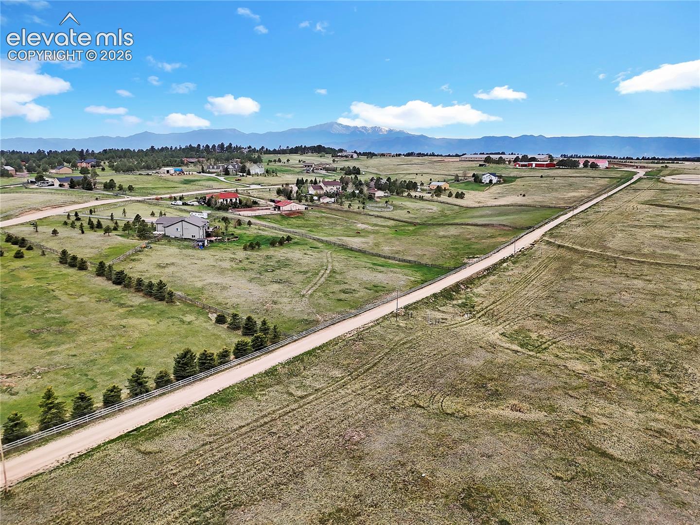 Expansive acreage featuring rolling terrain, established perimeter fencing, and a mountain backdrop