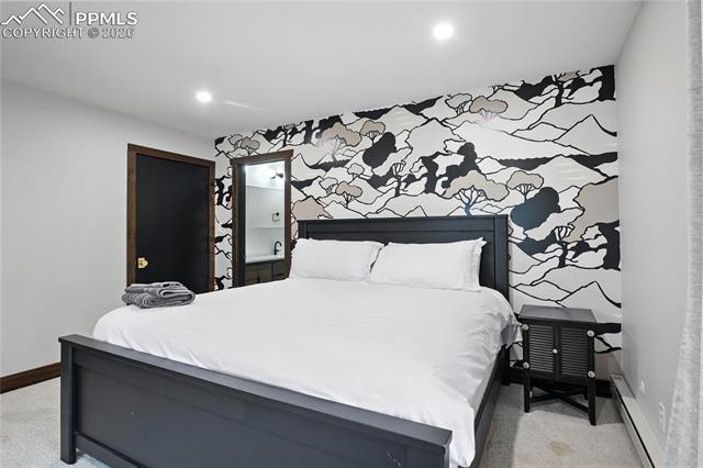Bedroom with light carpet, a baseboard radiator, recessed lighting, and an accent wall