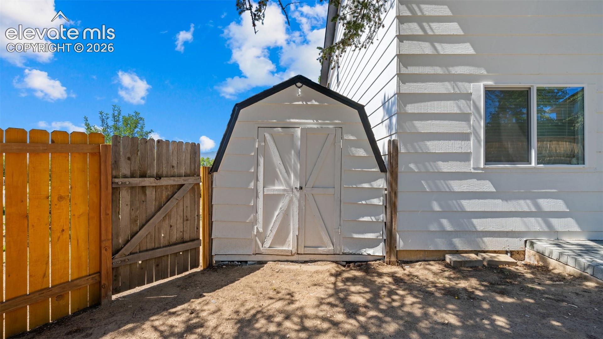 White exterior siding with a shed, a wooden fence, and a window