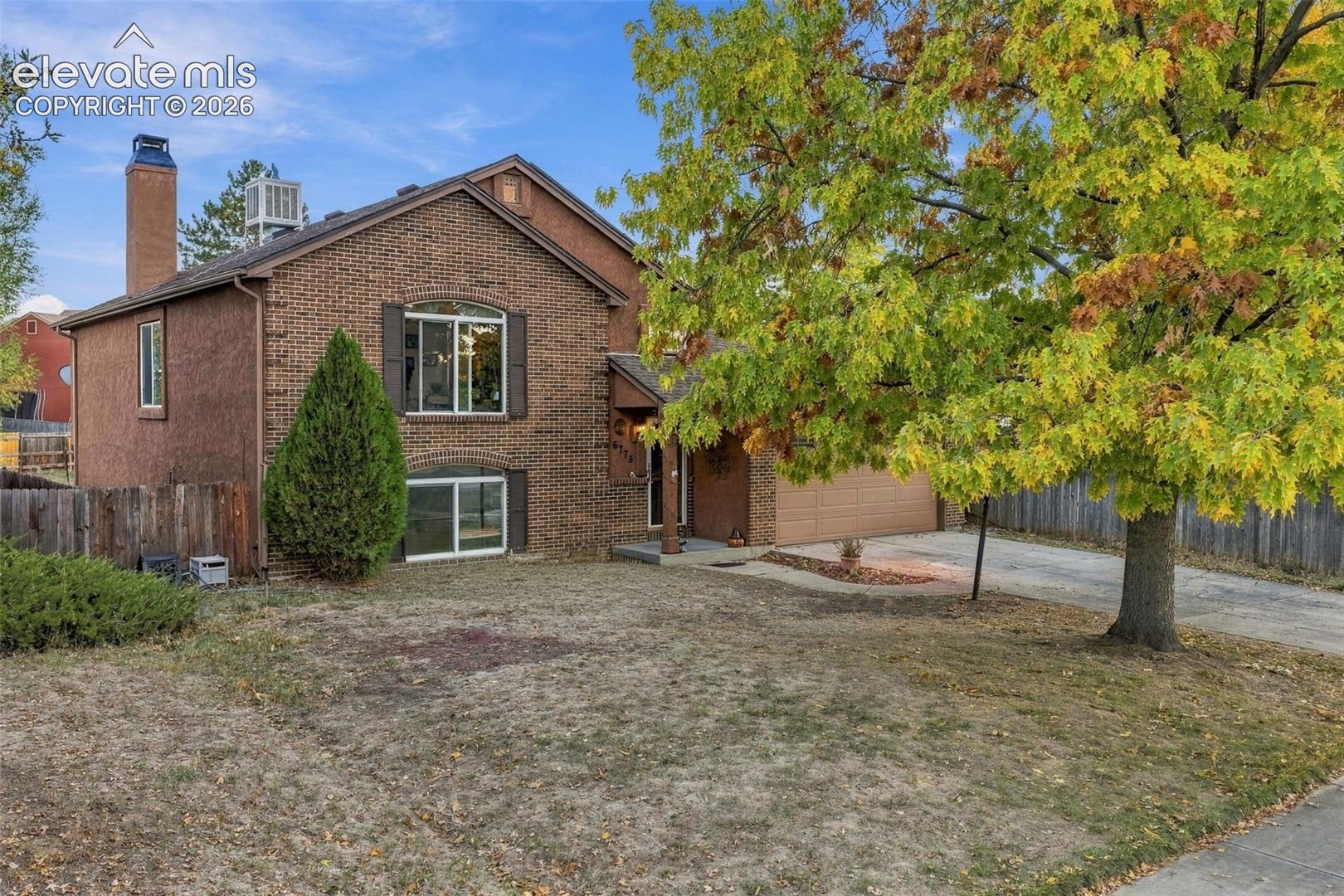Two-story brick exterior featuring a multi-gable roofline, attached garage, chimney, and large windows with arched detailing