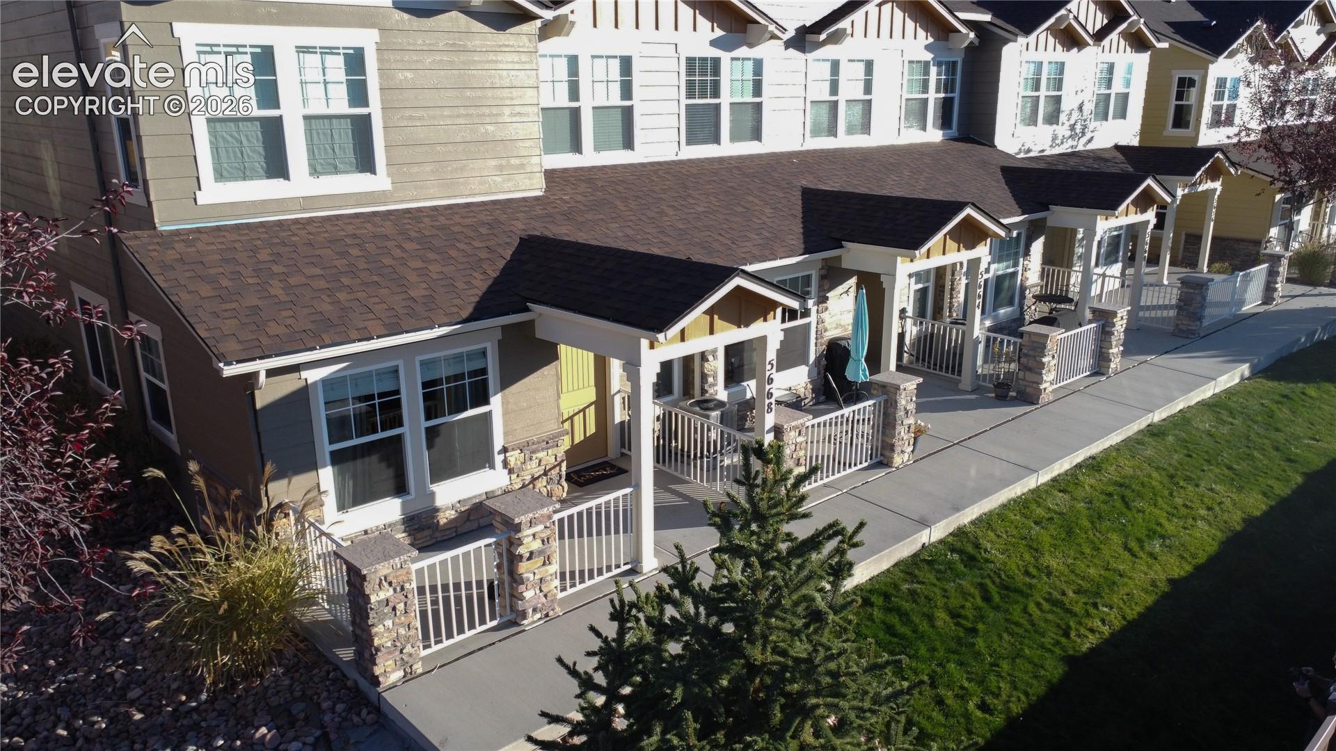 Multi-unit residence featuring horizontal lap siding, stone veneer accents, covered front entryways with white metal railings, and asphalt shingle roofing