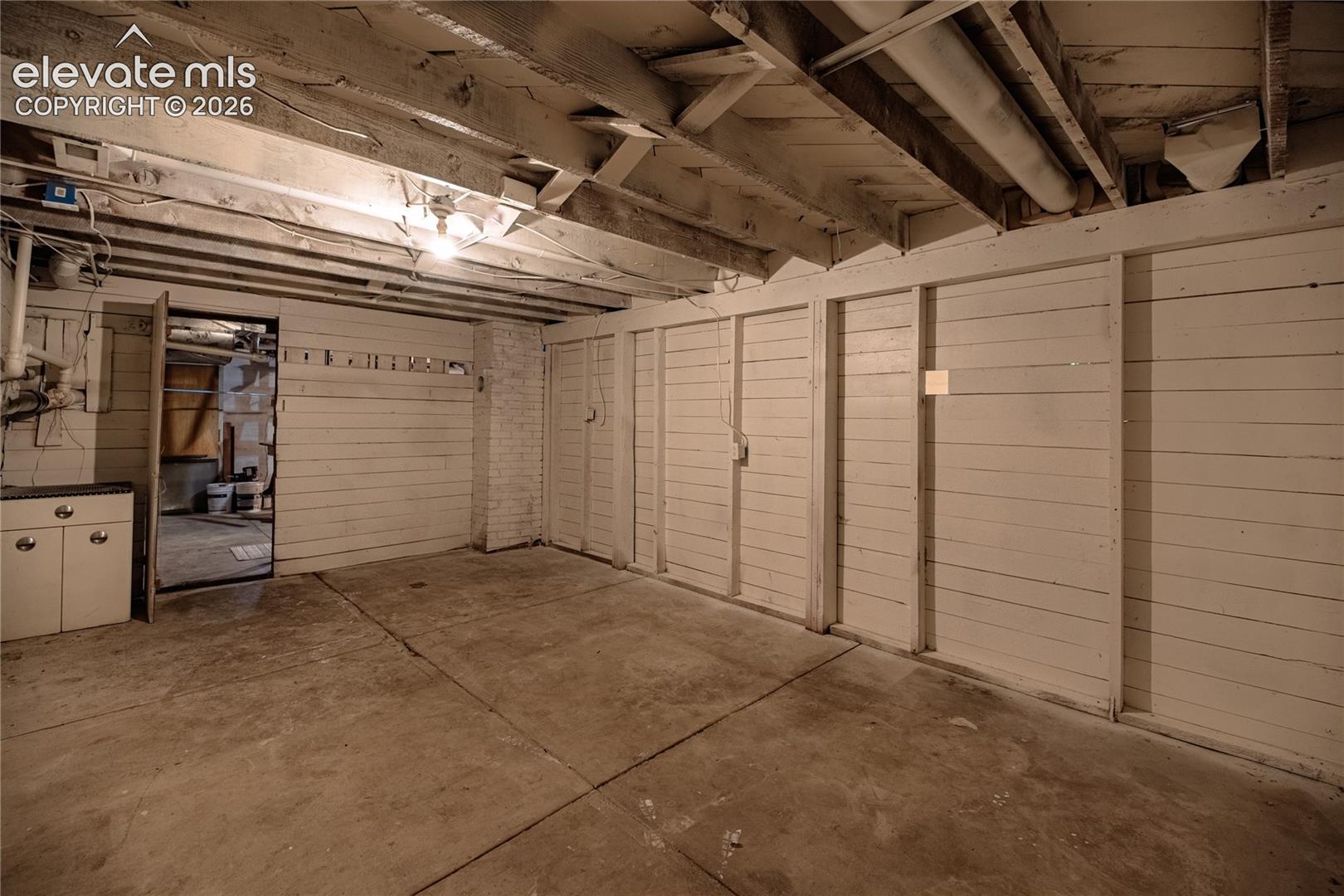 Exposed ceiling joists, concrete flooring, and built-in storage units