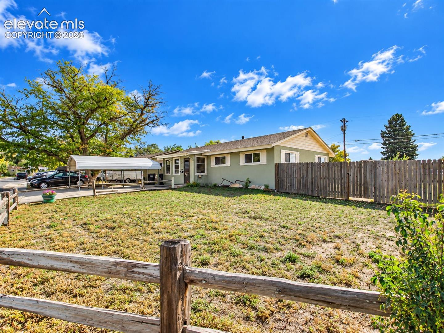Charming ranch-style home featuring a welcoming front entrance, a spacious front yard, and a covered carport with an extended driveway.