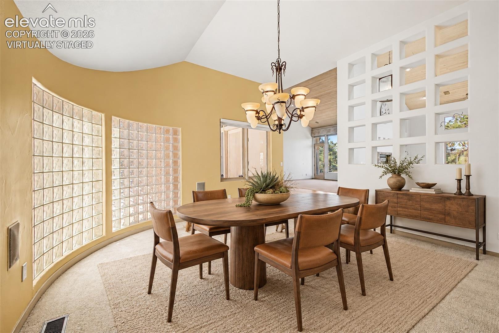 Virtually Staged
Curved wall with glass block windows, vaulted ceiling, decorative open shelving, and a chandelier lighting fixture
