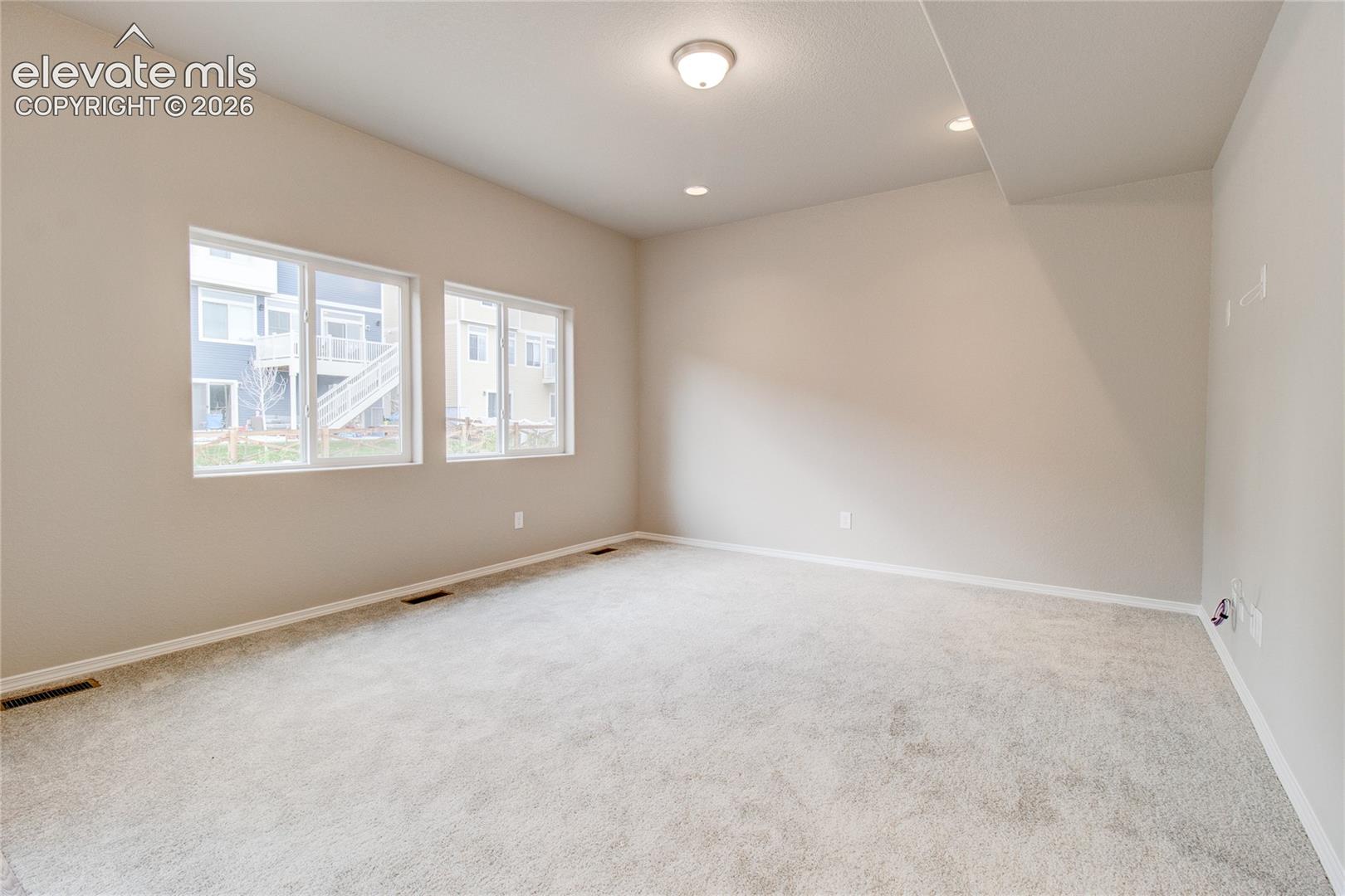 Neutral interior room featuring plush wall-to-wall carpeting, dual windows, and recessed lighting
