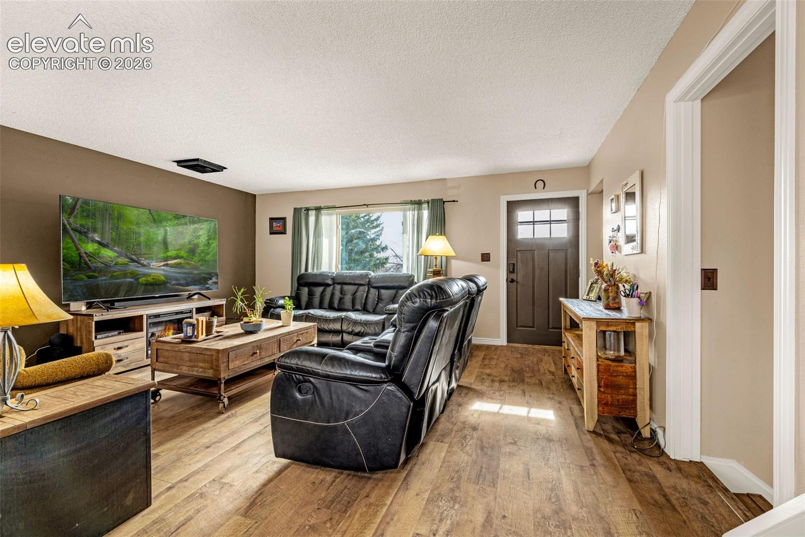 Living area featuring wood-finish flooring, a dark-toned accent wall, and a multi-pane front entry door