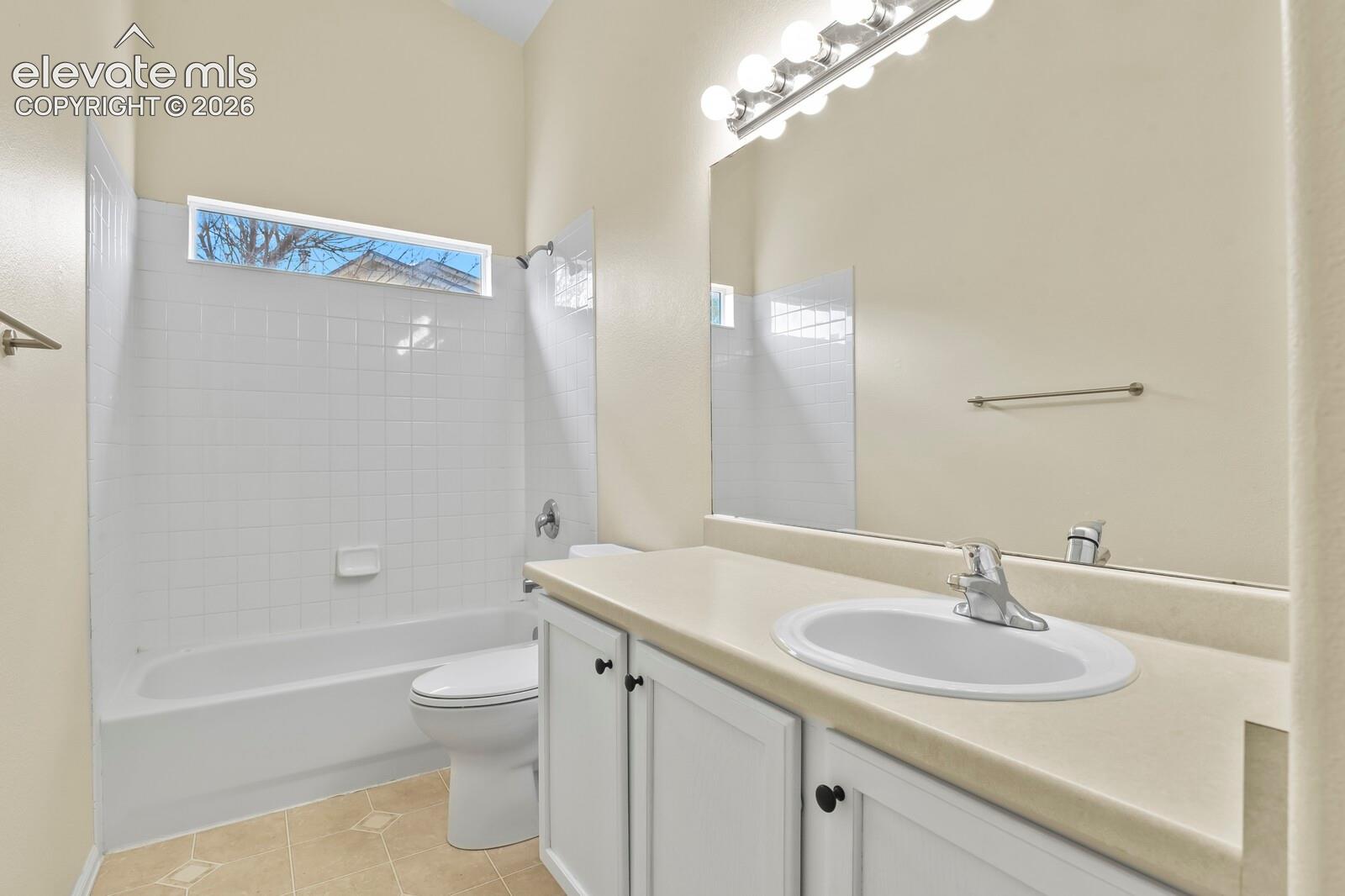 Bathroom featuring a single vanity with a white basin, a full-width mirror, and a wall-mounted light fixture