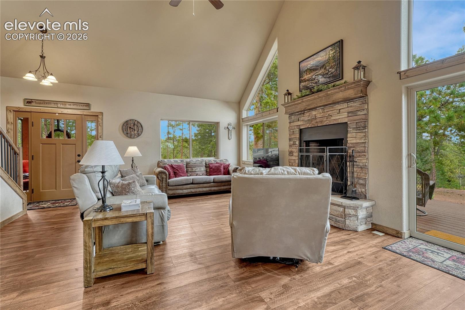 Vaulted ceilings, wood-finish flooring, stone-faced fireplace with a wood mantel,