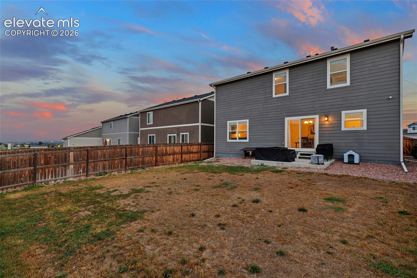 Exterior featuring gray siding, white-framed windows, and a concrete patio