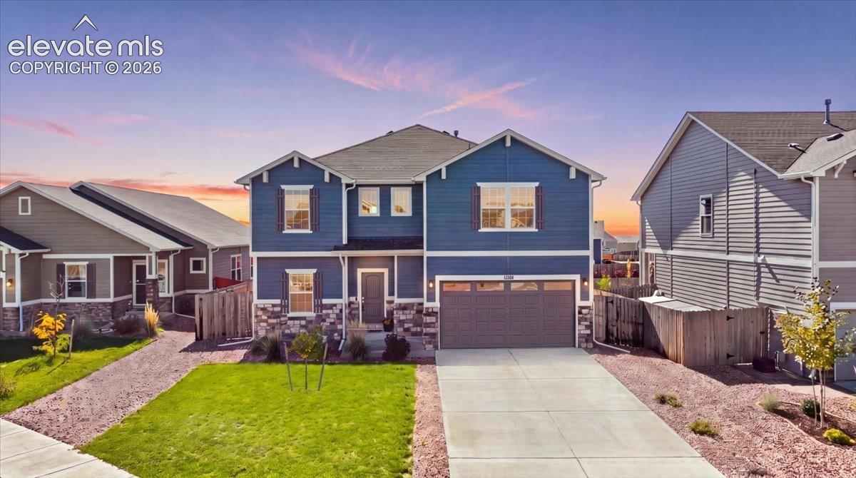 Two-story residence featuring blue horizontal siding, stone veneer accents, an attached two-car garage, and a concrete driveway