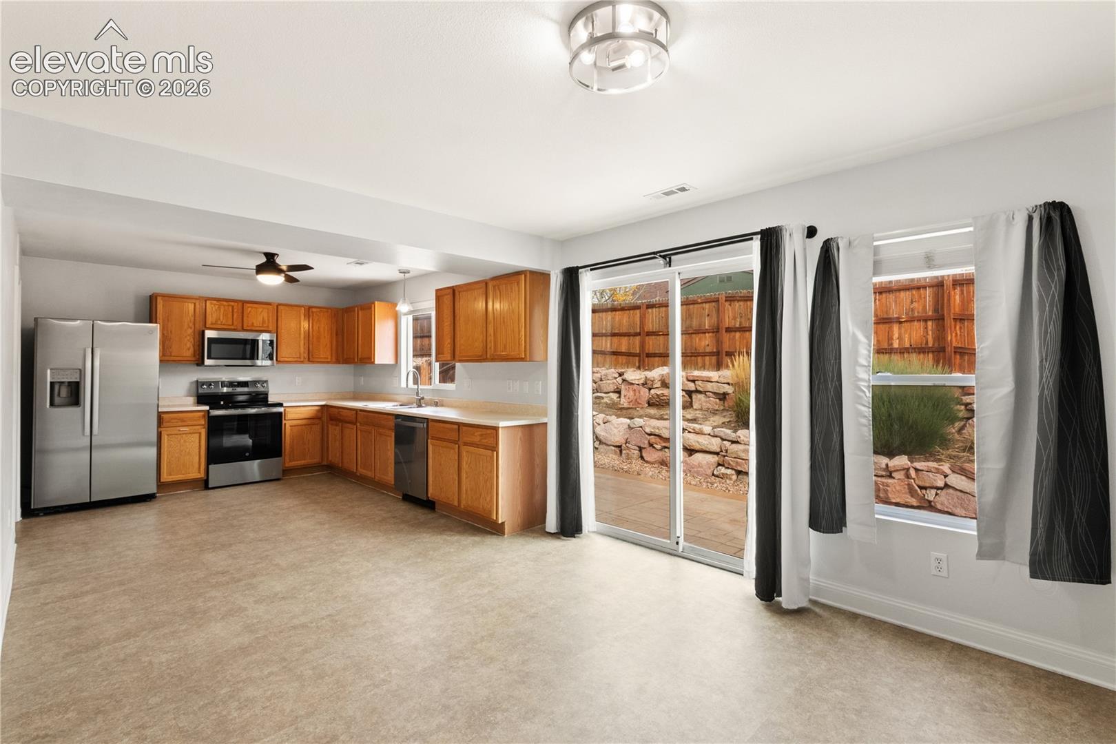 Kitchen featuring wood cabinetry, stainless steel appliances, sliding glass doors, and recessed ceiling lighting
